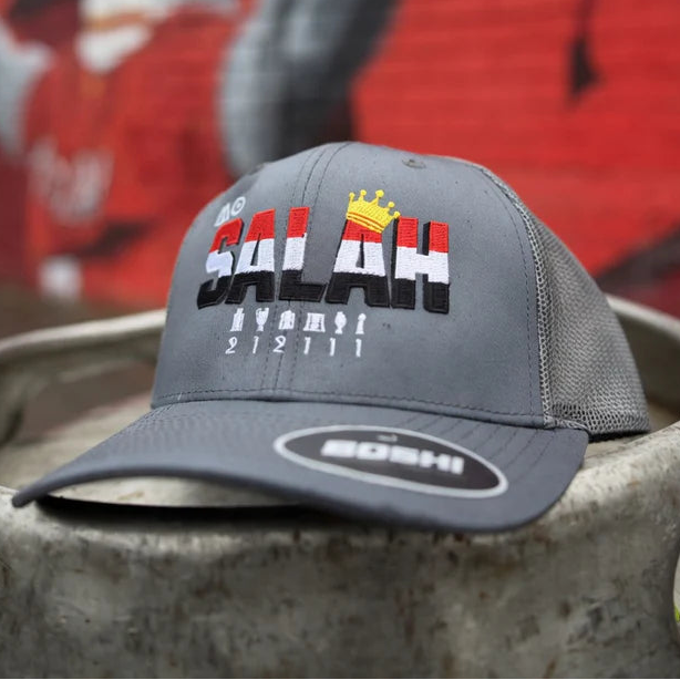 Gray cap with 'SALAH' branding on a metal surface with a colorful mural in the background